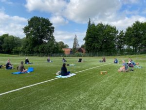 Teamsitzung mit viel Abstand auf dem Rasen