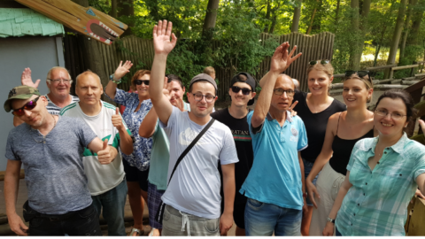 Fröhliche Menschen im Holiday Park winken in die Kamera.