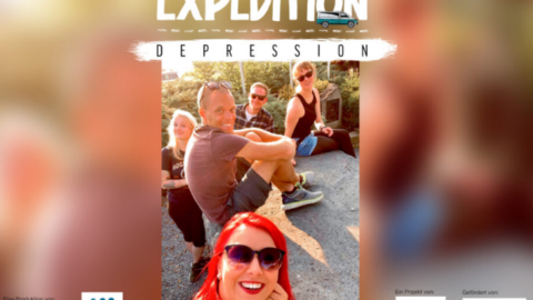 Mehrere Personen sitzen auf dem Boden und lächeln in die Kamera