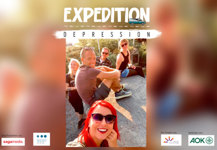 Mehrere Personen sitzen auf dem Boden und lächeln in die Kamera