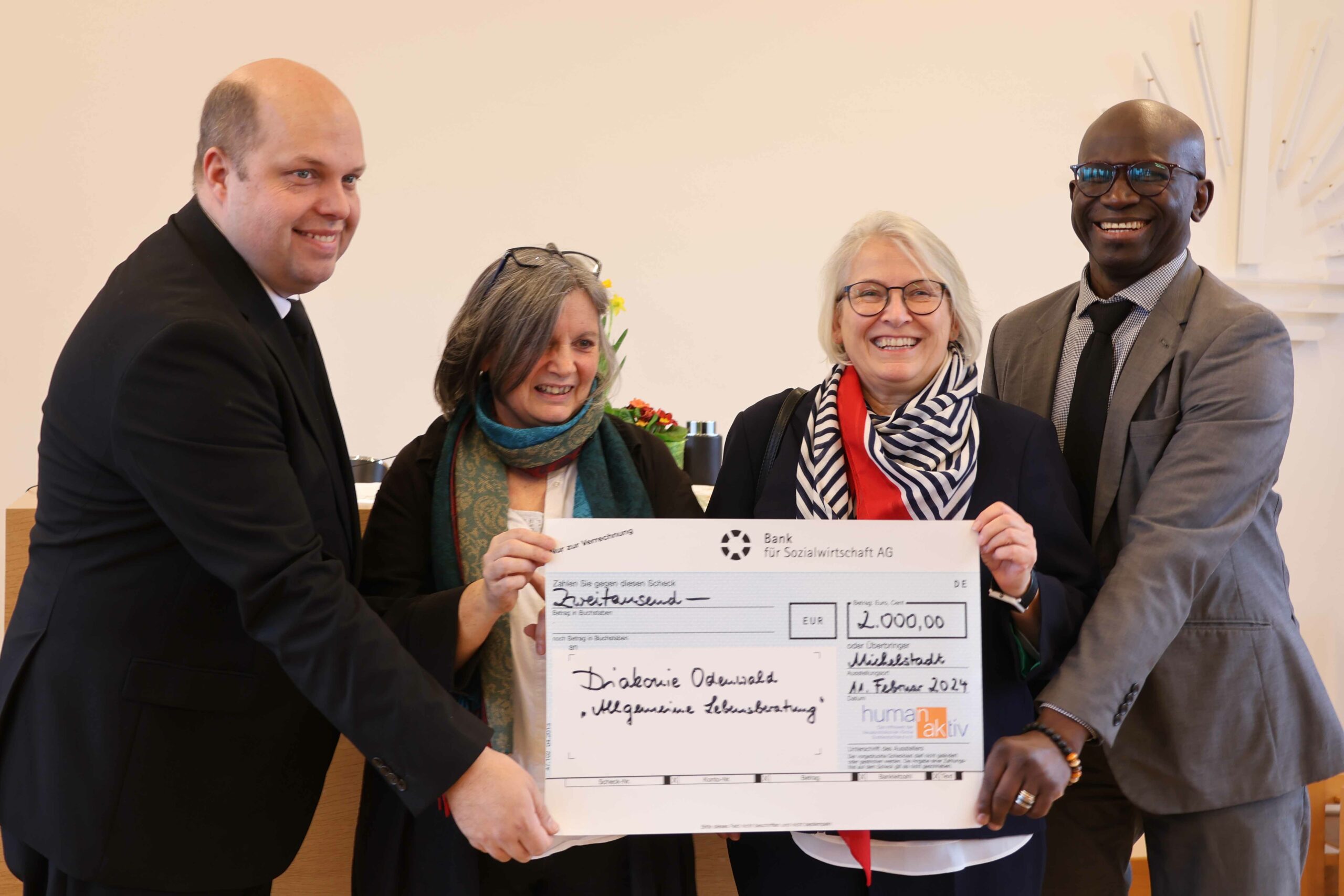 Mehrere Personen lachen in die Kamera bei einer Scheckübergabe von der Neuapostolischen Kirche an die Diakonie